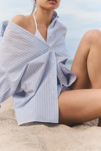 Detail of loose blue striped cotton shirt fabric with buttons for summer beach wear