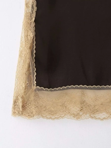 Détail de tissu satiné noir avec bordure en dentelle florale dorée sur l'ourlet