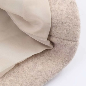 Gros plan sur le tissu en laine avoine épais et la doublure en satin lisse de ce manteau