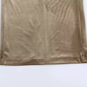 Detailed close-up of metallic velvet fabric with elegant pleats and bronze-gold shimmer
