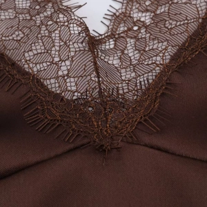 Macro detail of brown satin camisole featuring delicate eyelash lace trim at the neckline