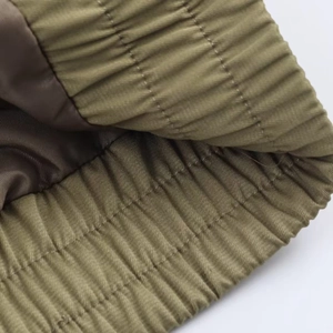 Close-up of olive green jacket with elastic ribbed hem and brown lining detail