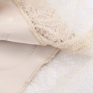 Vue macro détaillée de la dentelle florale fine et du satin lisse cousus sur la jupe midi