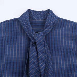 Detailed close-up of navy plaid shirt collar featuring elegant self-tie neck strings