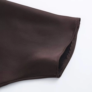 Gros plan sur l'ourlet de la robe en satin montrant les coutures et le tissu chocolat
