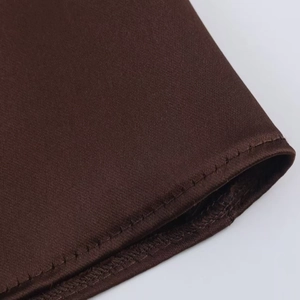 Close-up of deep brown satin fabric with professional single-needle stitching and neat hem