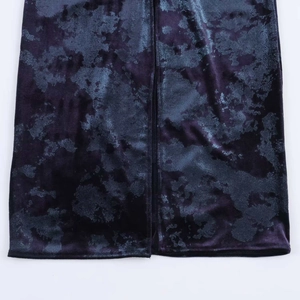 Close-up of elegant velvet dress hem featuring metallic abstract texture and slit detail