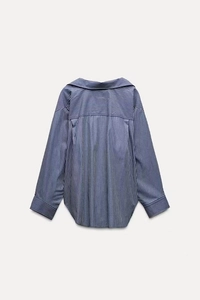 Detail view of the back of a blue and white striped long-sleeved shirt with curved hem