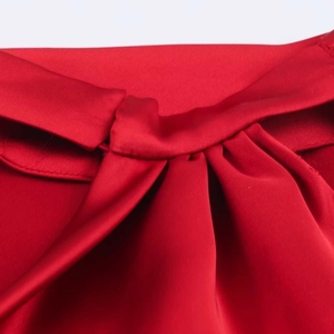 Détail d'une robe en satin rouge avec nœud élégant et texture de tissu plissé soyeux