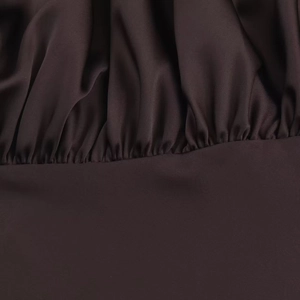 Vue macro d'un tissu en satin marron foncé avec des plis détaillés et des coutures fines