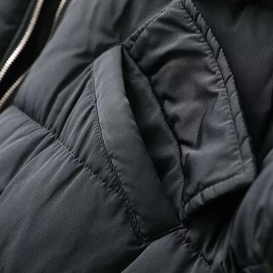 Detailed close-up of a quilted black winter jacket with windproof fabric and side pocket