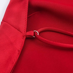 Détail d'une robe en satin rouge avec un anneau métallique argenté et une bretelle fine