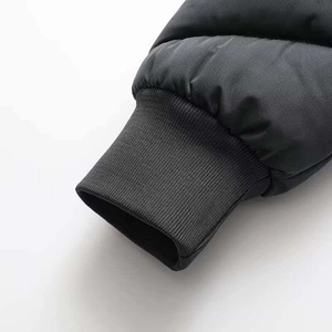 Detail of ribbed knit cuffs and quilted fabric on a black winter jacket for wind protection