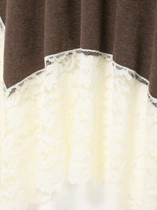 Close-up of deep brown fabric with white floral lace trim detail on the dress hem