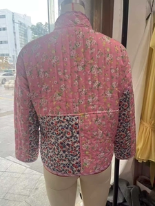 Detail of pink floral quilted jacket featuring patchwork design and vertical stitching