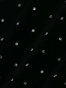 Detail shot of black velvet fabric with silver square rhinestones in a grid pattern