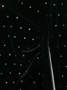 Detailed close-up of black velvet fabric with shiny silver square rhinestones and pleats