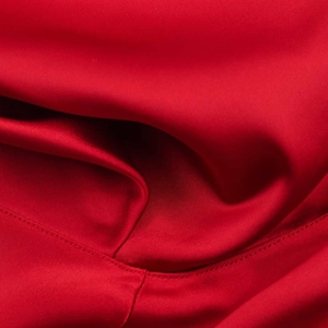 Gros plan sur la texture du satin de soie rouge avec détails de couture sur l'ourlet