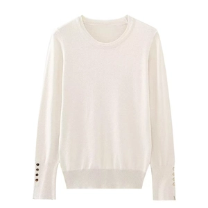 Detail of cream long sleeve knit top with decorative brown buttons on the ribbed cuffs