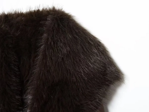 Detailed view of the dark brown thick faux fur collar on the long winter coat