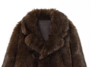 Detailed close-up of dark brown faux fur collar and shoulder texture on a fashion jacket
