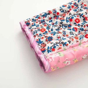 Detailed close-up of quilted floral fabric showing pink striped borders and precise stitching