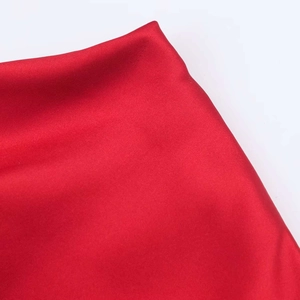 Détail du tissu satiné rouge vif montrant une texture lisse et un éclat de haute qualité