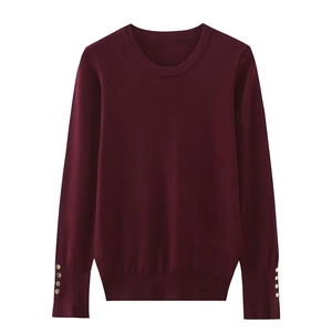 Detail of burgundy knit sweater showing golden decorative buttons on long sleeves cuff