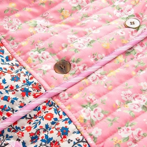 Detail of quilted floral jacket featuring contrast patterns and brown resin button