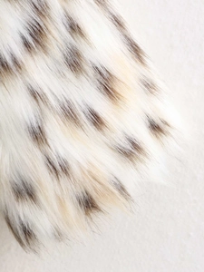 Detailed close-up of fluffy faux fur fabric with realistic snow leopard animal spots