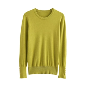 Detailed macro view of long-sleeve knit top with gold decorative buttons on the cuffs