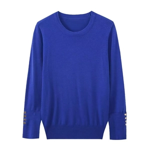 Detail of royal blue knit sweater sleeve showing four gold buttons on the cuff