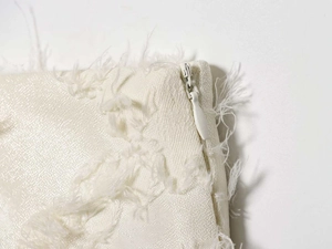 Detail of invisible zipper on cream white midi dress with textured feather fringe fabric