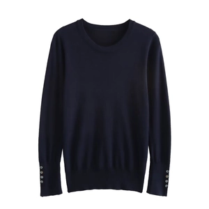 Detailed close-up of a navy blue knit sweater featuring decorative silver buttons on the cuffs