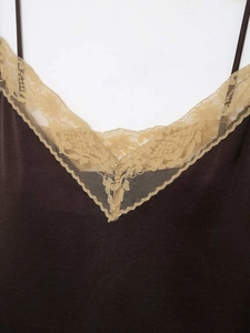 Close-up detail of dark brown satin top with delicate floral lace trim on V-neckline