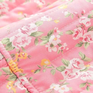 Macro shot of pink floral quilted fabric with detailed rose patterns and stitching