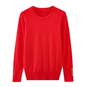 Close-up of red crewneck knit sweater featuring elegant gold buttons on ribbed cuffs