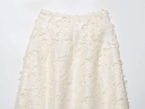 Close-up of the cream midi skirt with intricate 3D fringe and textured jacquard details