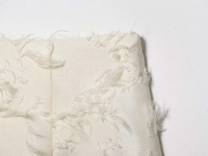 Detail shot showing 3D floral jacquard and feather textures on cream midi skirt