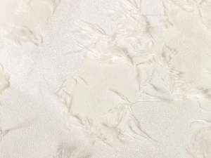 Close-up of cream white floral jacquard fabric with delicate eyelash fringe details