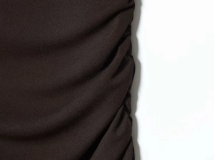Detail of ruched dark brown fabric texture showing elegant pleats and vertical folds