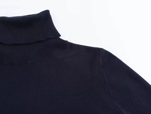 Detail shot of the turtleneck collar and shoulder on this navy blue knit sweater