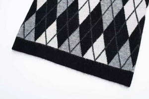 Detalle del patrón de rombos en tejido de punto con dobladillo negro acanalado y textura