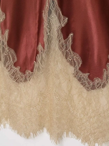 Détail de jupe en satin bordeaux avec dentelle dorée délicate et finition de qualité