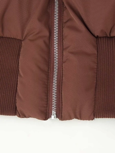 Detail of coffee brown padded jacket featuring silver metal zipper and ribbed hem