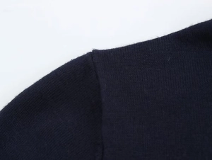 Detailed close-up of seamless shoulder stitching on a navy blue knit sweater