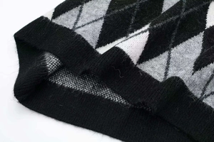 Macro view of argyle knit dress showing classic black grey diamond pattern and ribbed hem