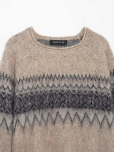 Détail macro de la texture en maille douce et motif jacquard géométrique sur le pull beige