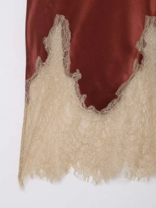 Détail de la jupe taille haute en satin rouge vin avec un bord en dentelle beige élégante