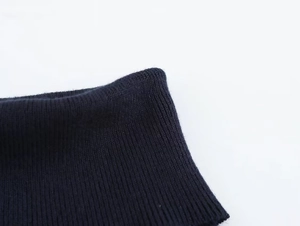 Detailed macro view of the ribbed knit fabric and cuff texture on a dark winter sweater